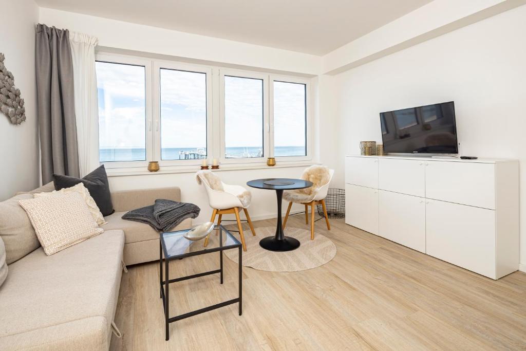 a living room with a couch and a tv and a table at Ostsee Suite 4 - Strandperle in Niendorf