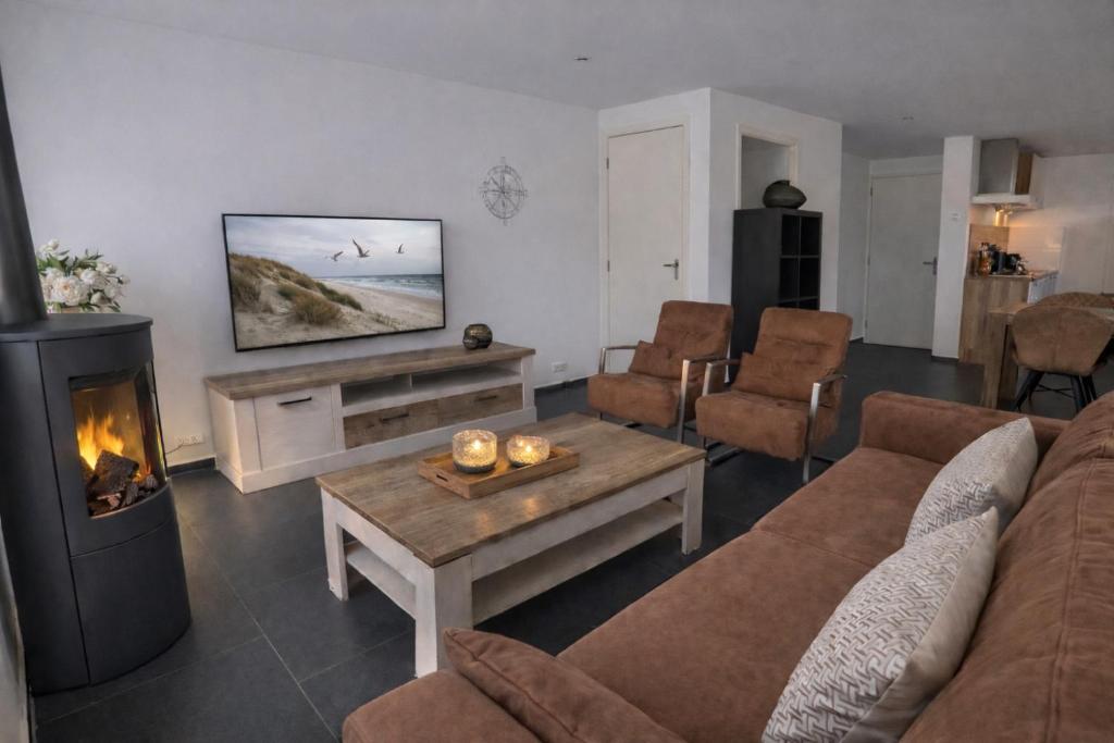 a living room with a couch and a fireplace at Ballumerhoeve Tree Lodge in Ballum