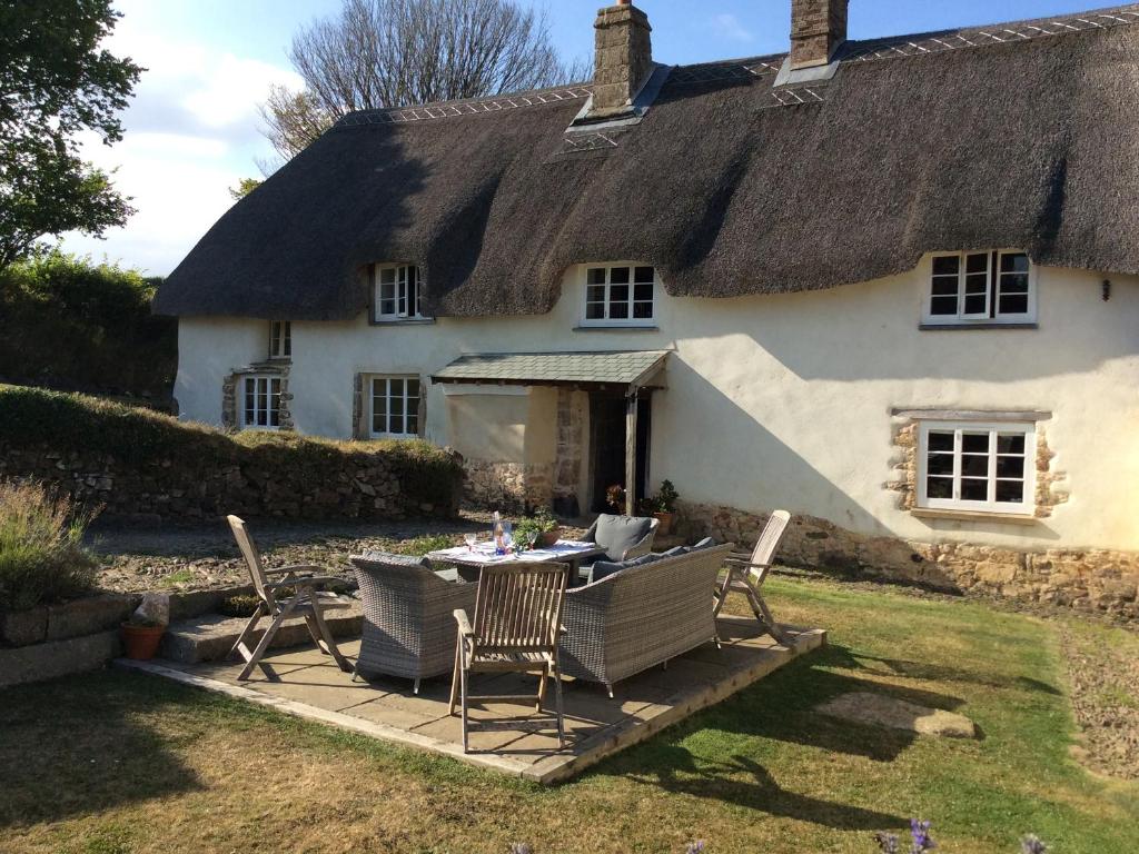 a thatched cottage with a table and chairs at Westacombe Farmhouse in Exeter