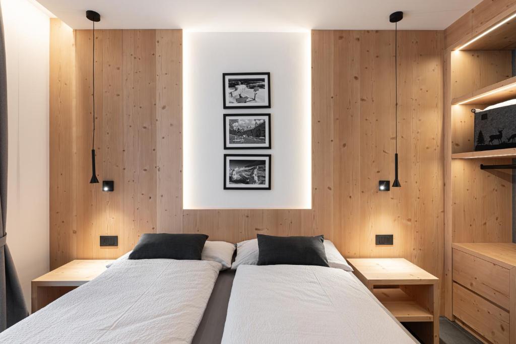 a bedroom with two beds and wooden walls at Appartamento Rododendro in Andalo
