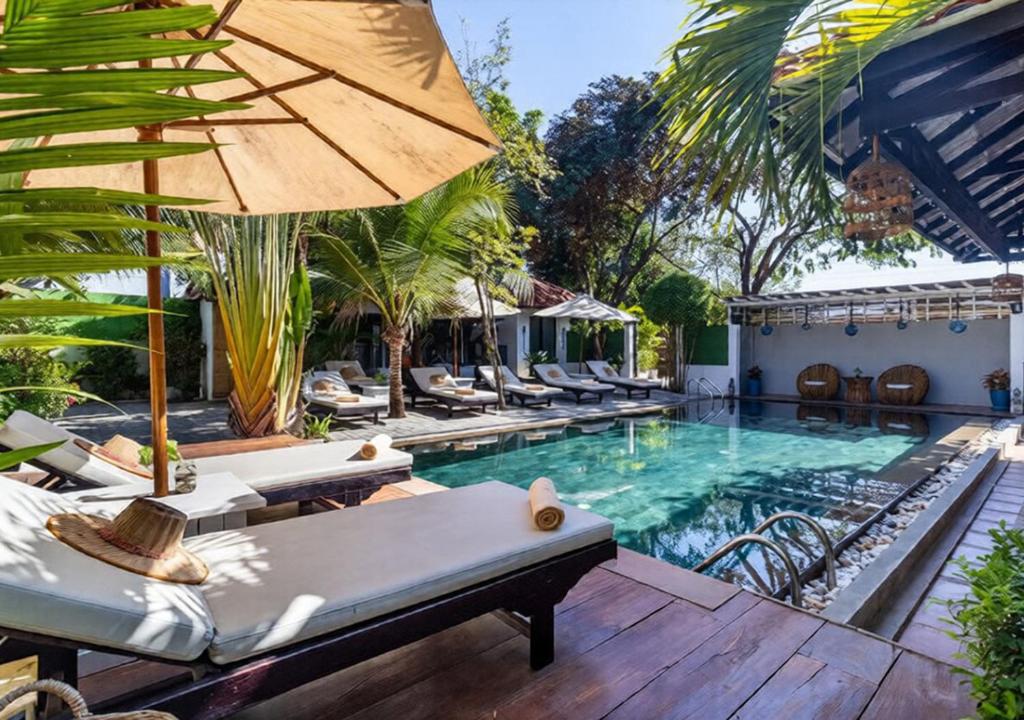 an outdoor pool with chairs and an umbrella at Angkor Eden Boutique Hotel in Siem Reap