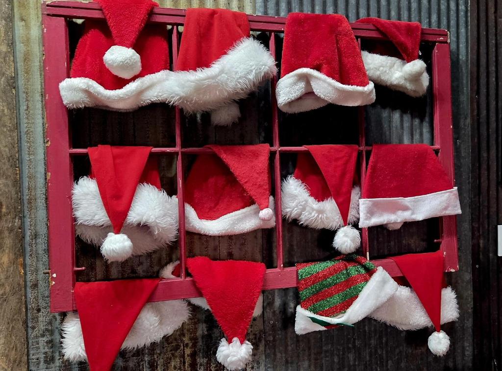 a bunch of santa hats hanging on a wall at Rural life on a real Christmas tree farm! Hallmark experience! in Ozark