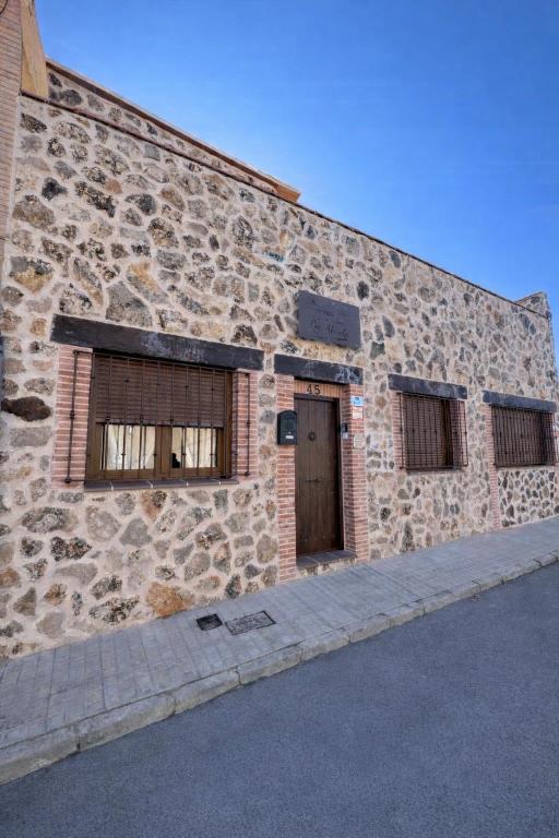 a stone building with two windows and a door at Los Abuelos Carreros in Consuegra