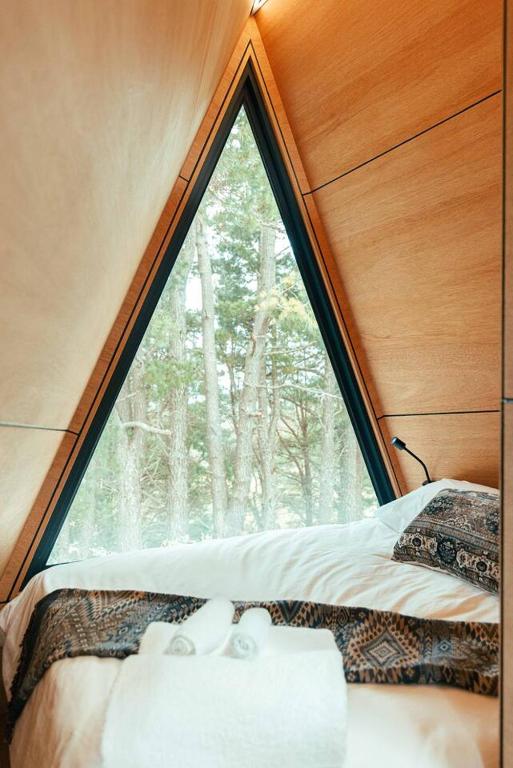 a bed in a room with a large window at Exclusive luxury tiny home in an idyllic setting in Glenquarry