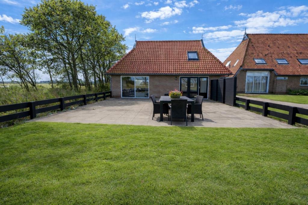 a patio with a table and chairs in front of a house at Ballumerhoeve t Pandje in Ballum