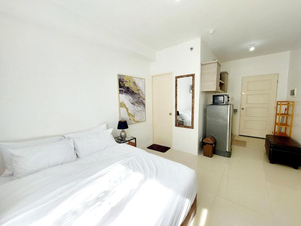 a bedroom with a white bed and a refrigerator at Affordable Stylish & Cozy Walk Up Condo in Minglanilla
