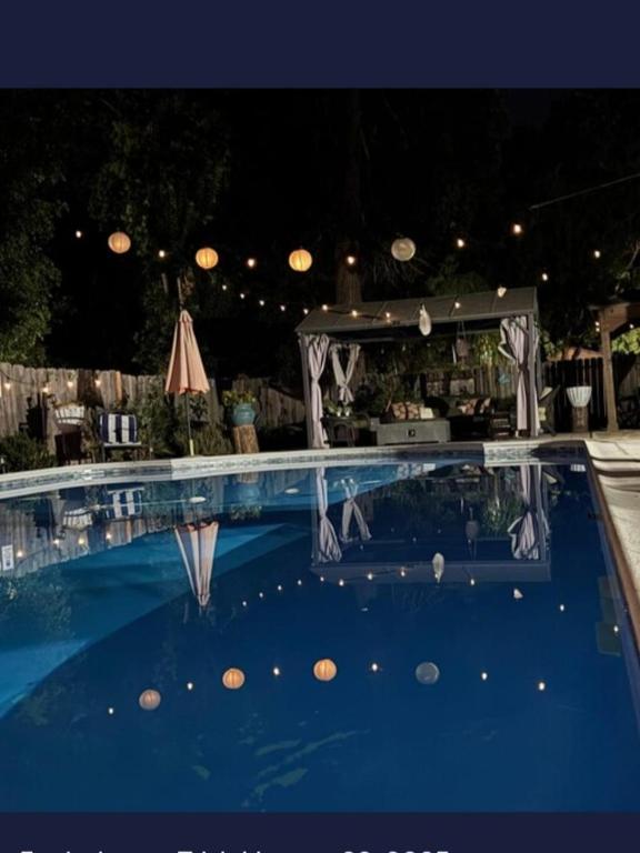 a swimming pool with a table and an umbrella at Garden Clara in Yuba City