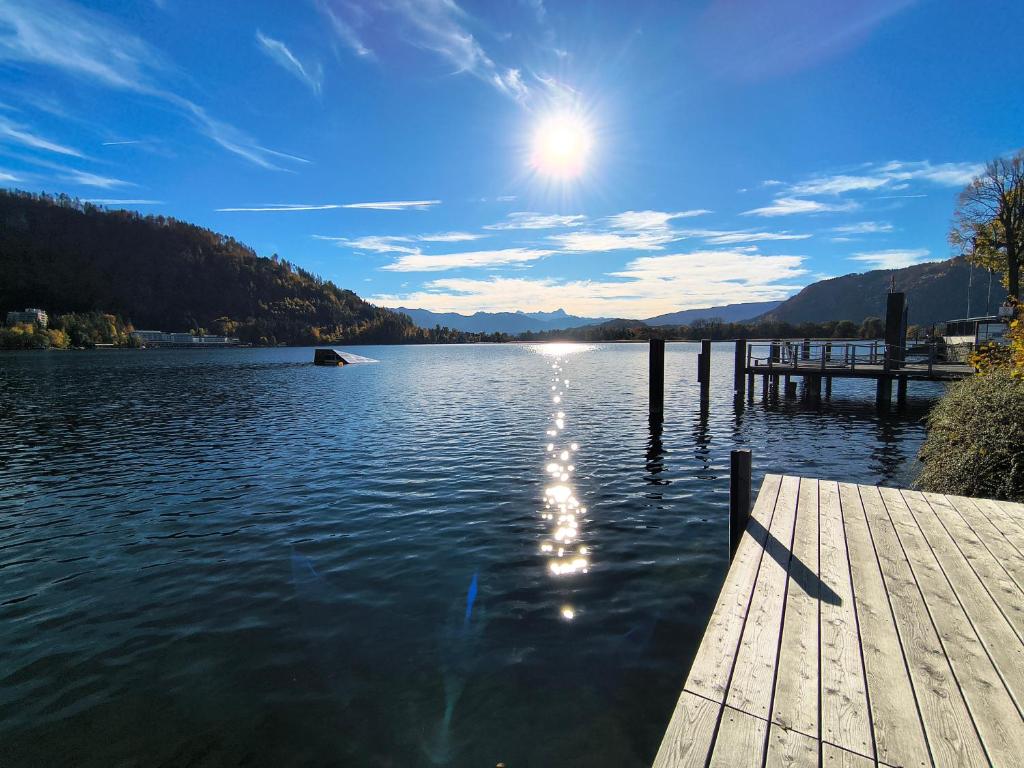 a dock on a lake with the sun in the sky at Appartement Seeleben in Bodensdorf