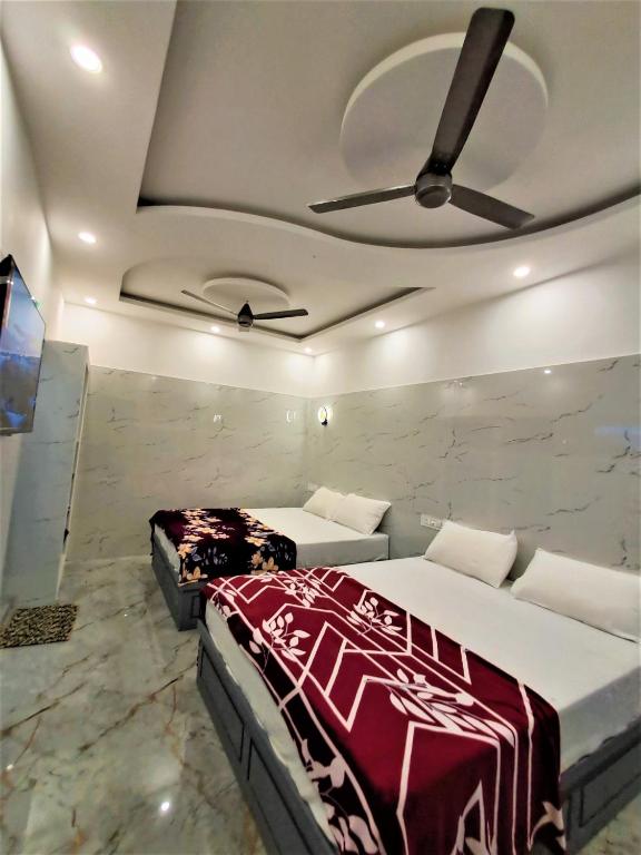 a bedroom with two beds and a ceiling fan at Amirtham Holiday Home in Kovakulam
