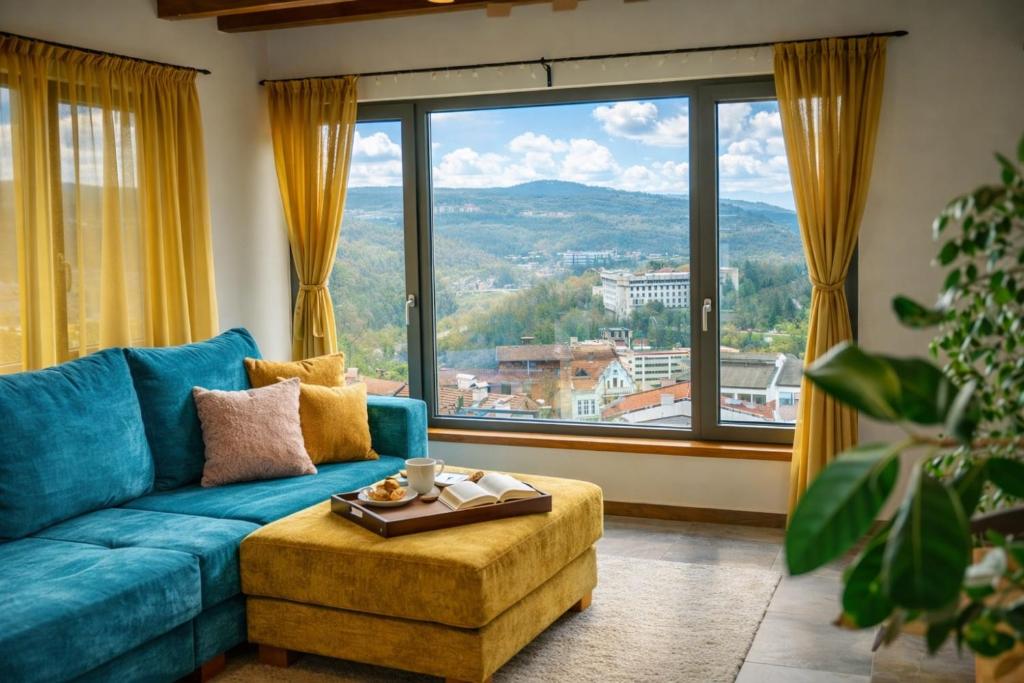 a living room with a blue couch and a large window at Studio54 Stunning View plus Free Parking in Veliko Tŭrnovo