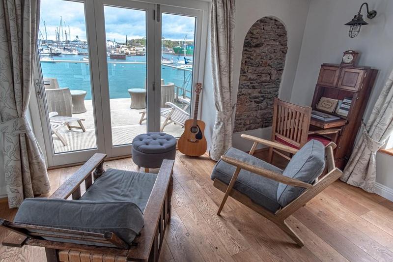 a living room with chairs and a view of the water at Waterfront Boathouse - Drift Cottage in Plymouth