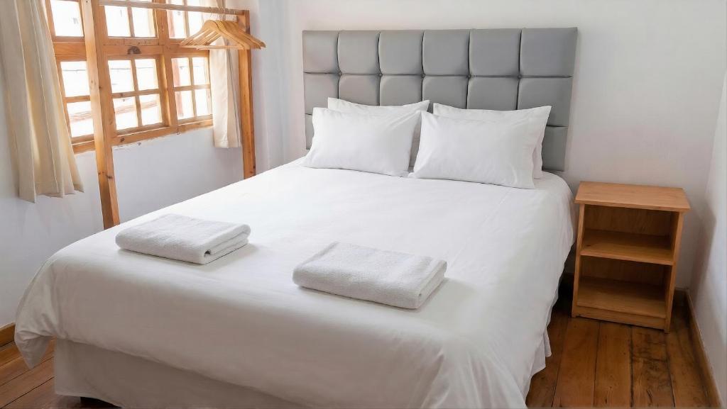a bedroom with a large white bed with two towels on it at Casa Don Jose B & B in Puno