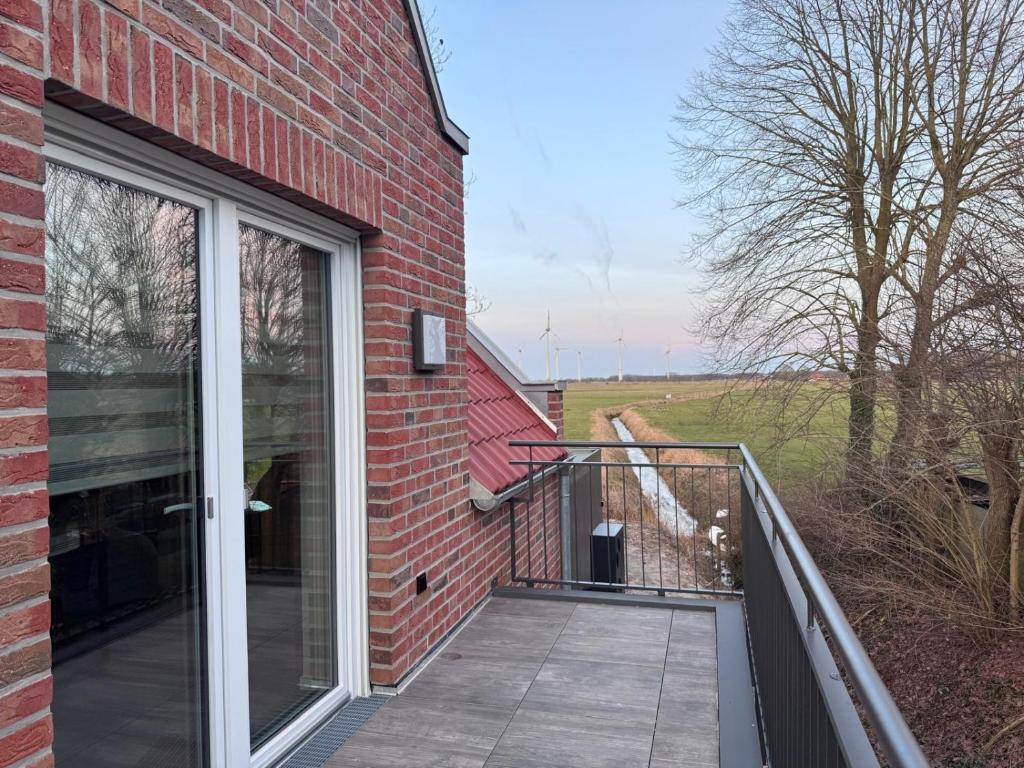 a balcony of a brick building with a sliding glass door at Ferienwohnung Schöne Aussicht in Hinte