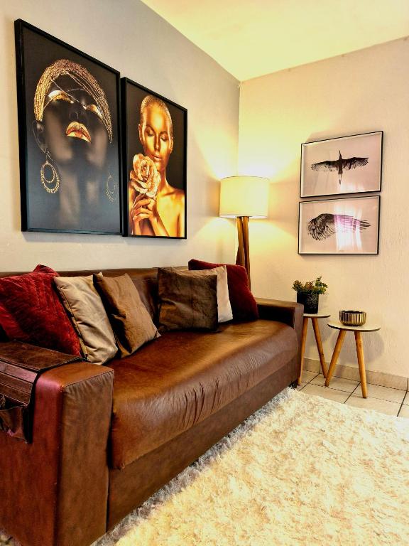 a brown couch in a living room with pictures on the wall at Pacífico Guest House Recife - Polo Médico e Universidades in Recife