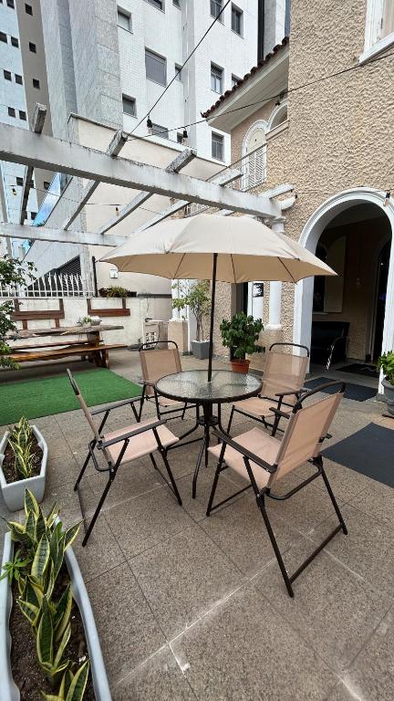 a table and chairs with an umbrella on a patio at Nuhh Hostel & Café in Belo Horizonte