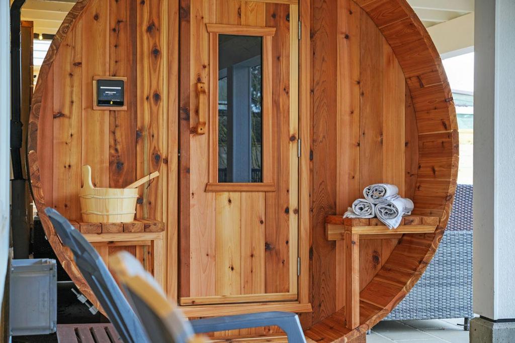 a wooden cabin with a round door on a porch at Private Cedar Sauna Retreat - Kitchenette, King Bed, Spa Bath - Deep Cove in North Vancouver