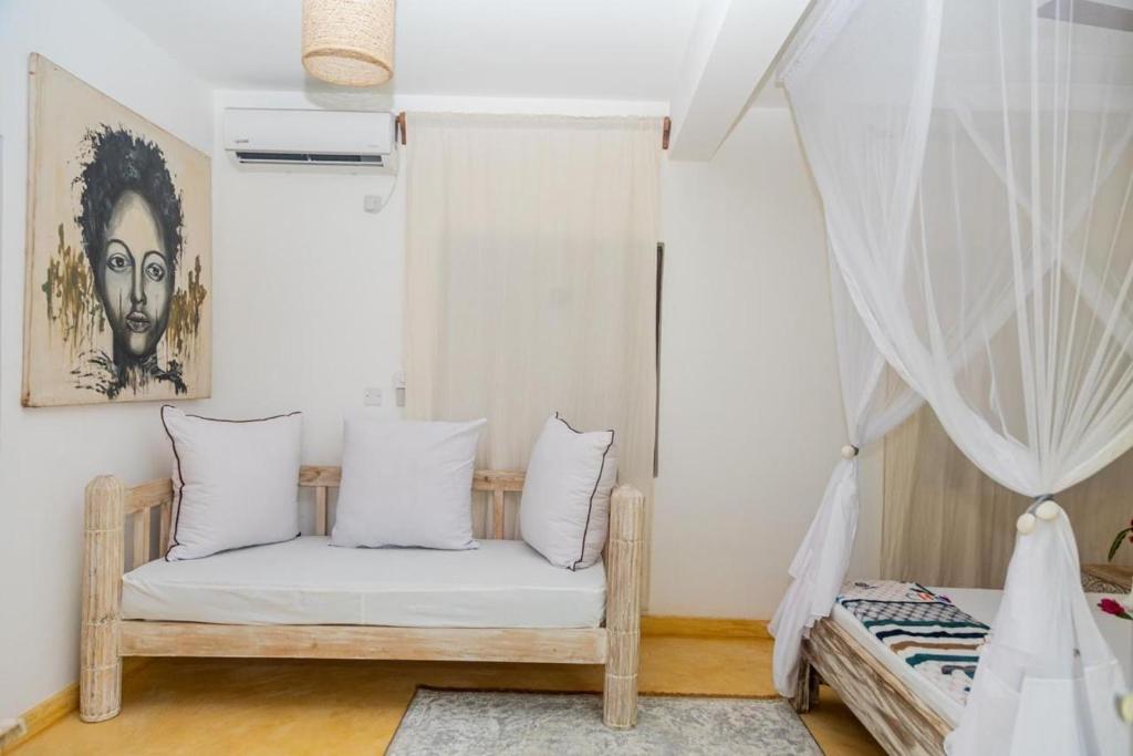 a room with a bed with white pillows at BREEZEACARDEs in Diani Beach
