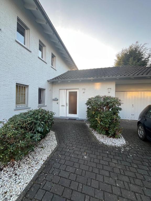 a white house with two bushes in front of it at Apartment Bielefeld-Brake - nähe Bahnhof -Parken im Hof in Bielefeld