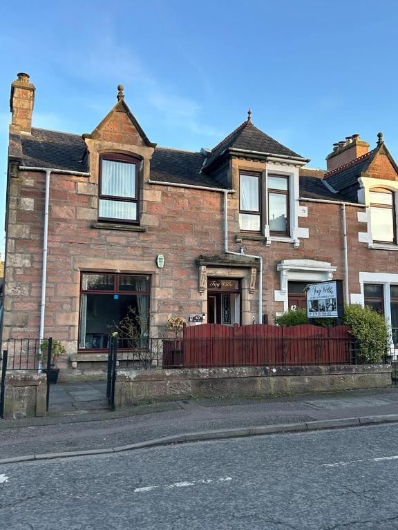 a brick house with a red fence in front of it at Tay Villa in Inverness