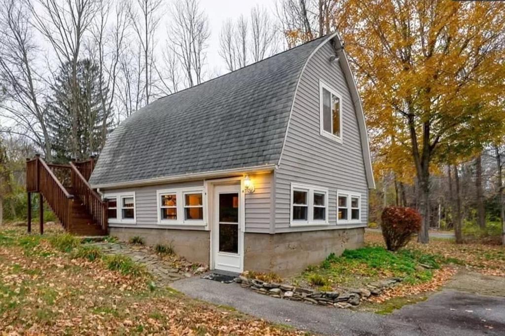 a small house with a gray roof and white doors at Chalet Cabin 7-Acres Pond! in Andover