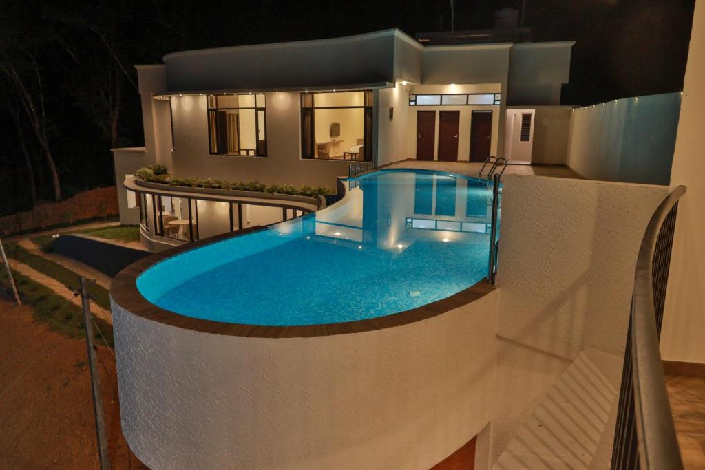 a swimming pool in front of a house at night at Serene Aqua Hills in Kozhikode