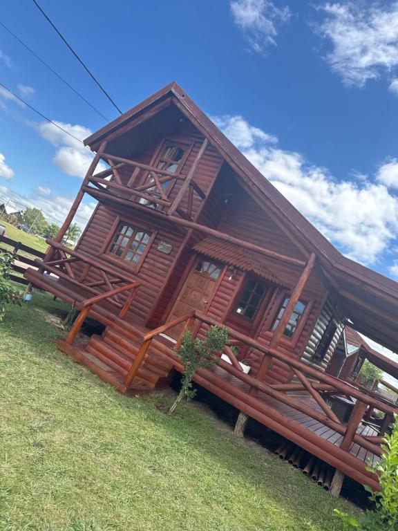 a large wooden cabin on a grass field at Cabaña El Guayabo in Villa Urquiza