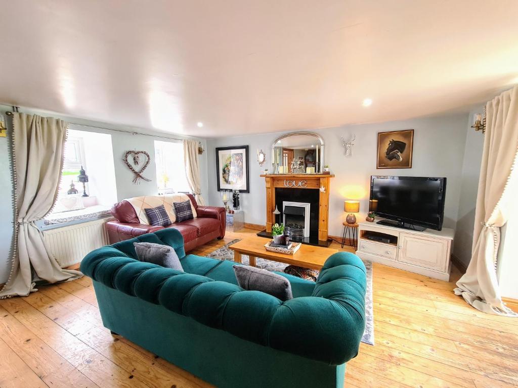 a living room with two couches and a tv at Cute Quirky Cottage in Llandow