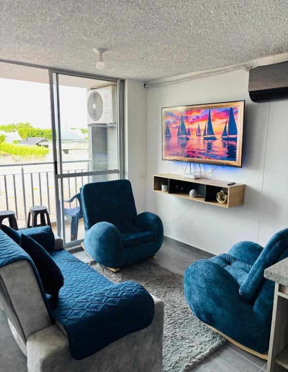 a living room with two blue chairs and a tv at Apartamento exclusivo en ricaurte Cundinamarca in Ricaurte