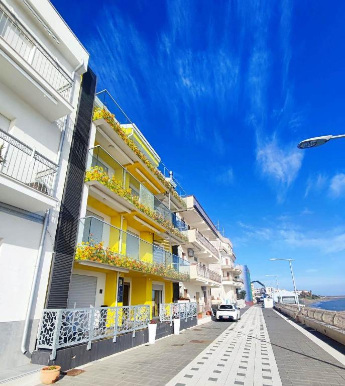 a yellow building with balconies and a car parked on a street at Yellow Dream B&B 2 in Torre Melissa