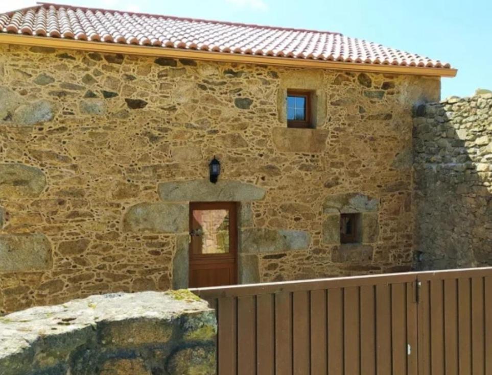 a stone house with a wooden door and a fence at Casa Candy in Muxia