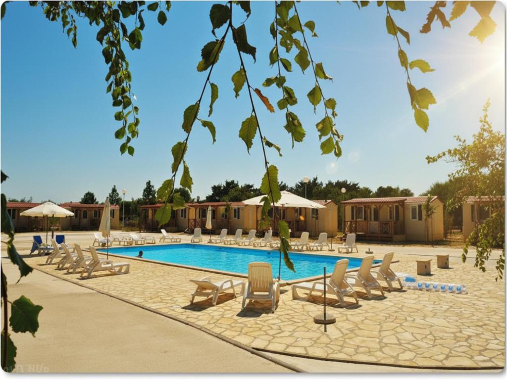 a swimming pool with lounge chairs and a resort at Mobile Homes Peroš in Zaton