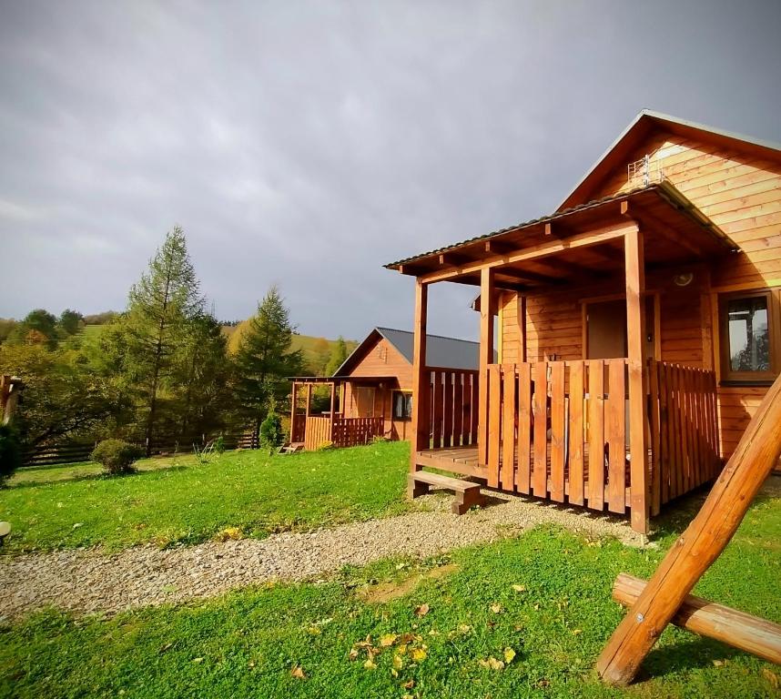 a wooden cabin with a porch in a field at Domki Tepakówka in Wołkowyja