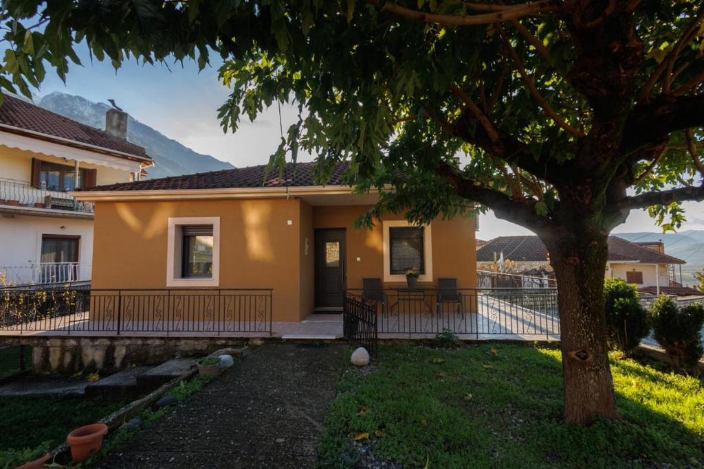 a yellow house with a tree in the yard at Η Μουριά in Konitsa