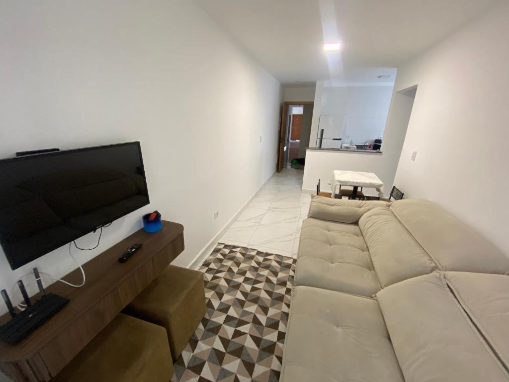 a living room with a couch and a flat screen tv at Atlântico 34 Guilhermina in Praia Grande