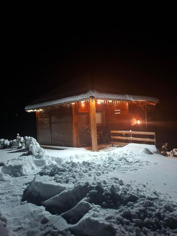 a cabin covered in snow at night with lights at Straza in Rožanstvo