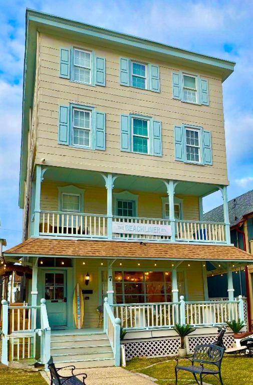 a large yellow house with a porch and a deck at Beachliner Hotel in Ocean Grove