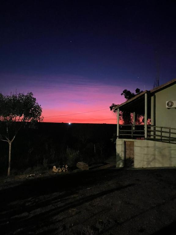 a building with a sunset in the background at Quintal de minas Pousada in Delfinópolis