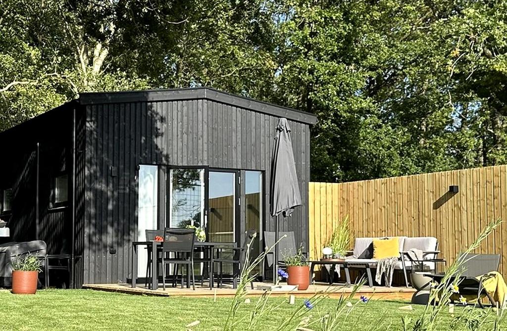 a black shed with a table and chairs in a yard at Skrylle Hideaway - cozy tiny house near Lund in Dalby
