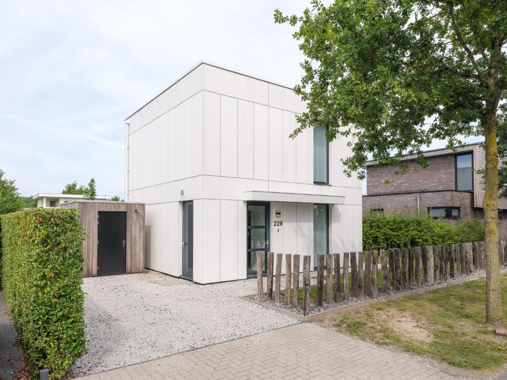a white house with a fence in front of it at Harderwold Villa - 228 in Zeewolde