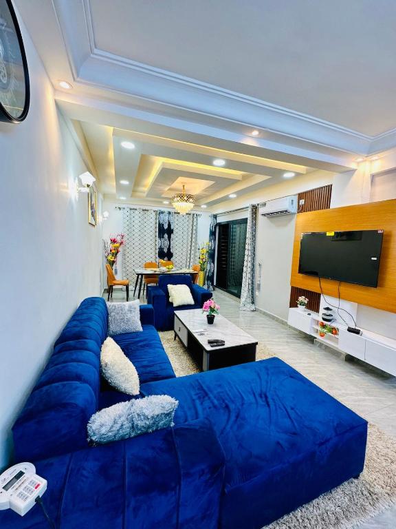 a living room with a blue couch and a flat screen tv at Magnifique Appartement meublé de 2 chambres avec GROUPE ELECTROGENE et ASCENSEUR in Douala