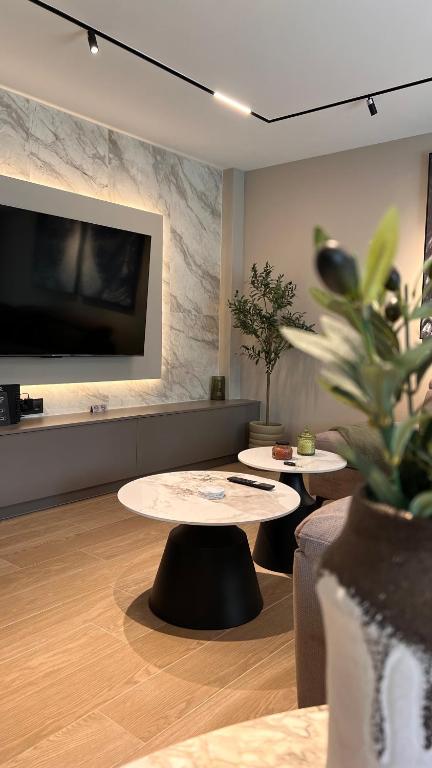 a living room with two tables and a tv at Olive Home in Alexandroupoli