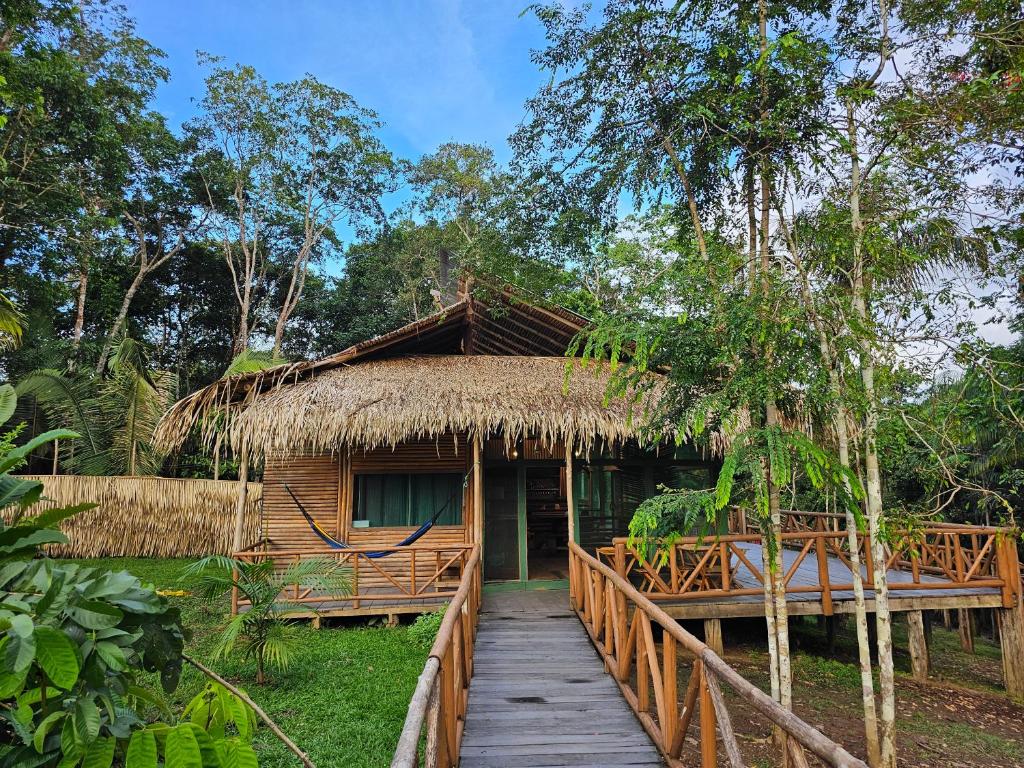 a wooden walkway leading to a hut with a thatched roof at Paroá Amazon Lodge in Manacapuru