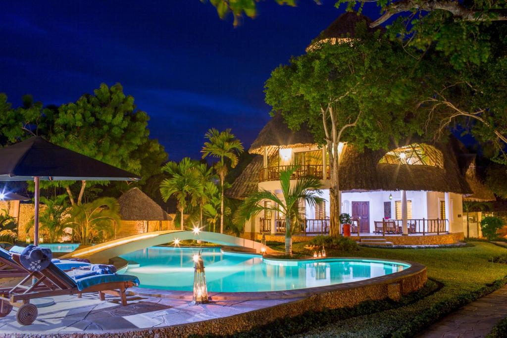 a resort with a swimming pool at night at Villa Kapungu with private C h e f, XXL pool & garden in Diani Beach