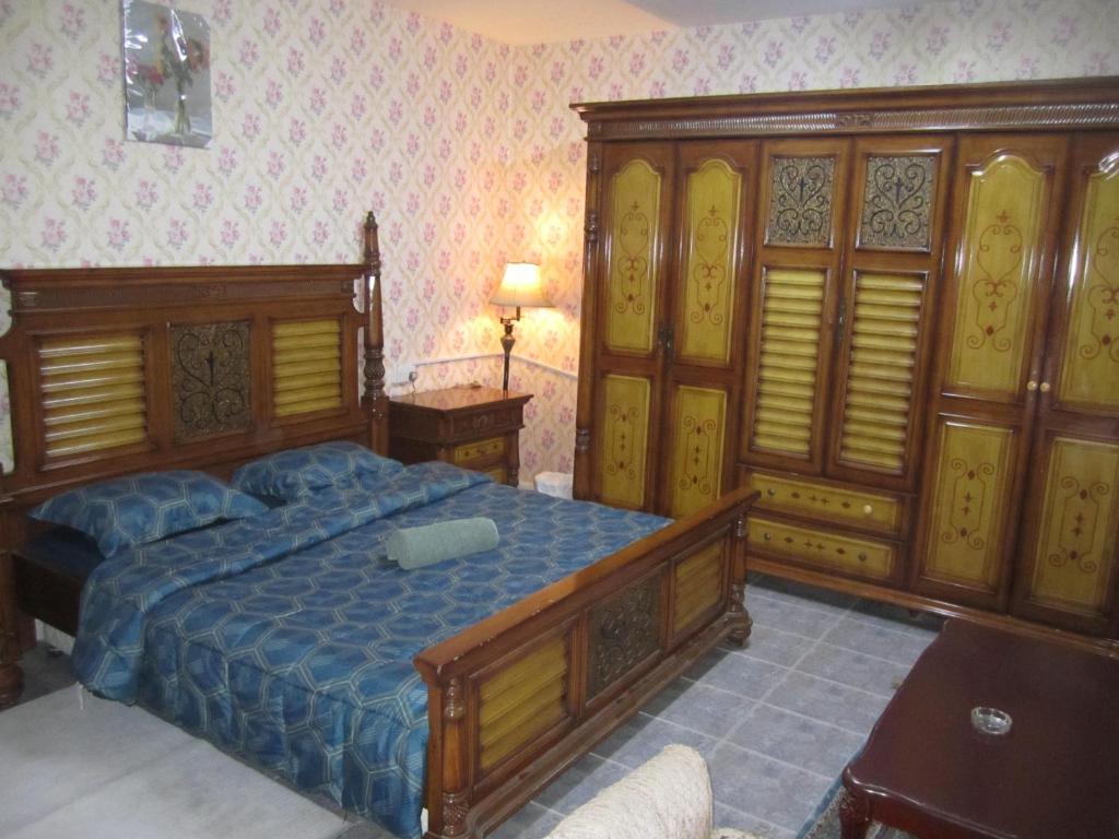 a bedroom with a large wooden bed and wooden cabinets at العين الهيلي مصباح ب 5 in Al Ain