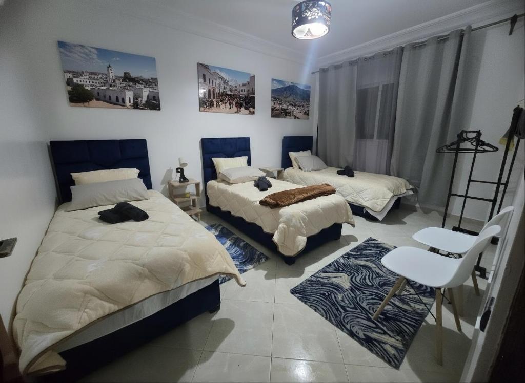 a bedroom with two beds and a chair at Hostel Dar Khelifa in Tétouan