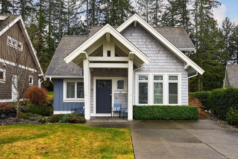 a small house with a blue door in a yard at Qualicum Landing Coastal Cottage in Qualicum Beach