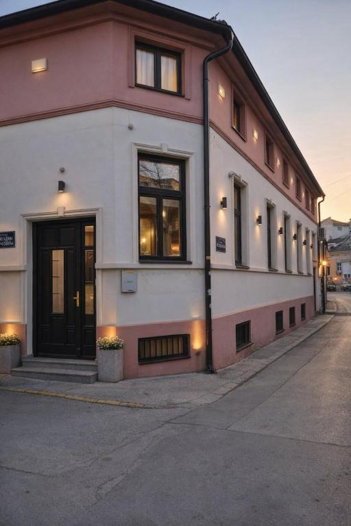 a white and pink building with windows on a street at IMAGINATOR RESIDENCE-Pool is extra pay- Parking 2 free space in Novi Sad