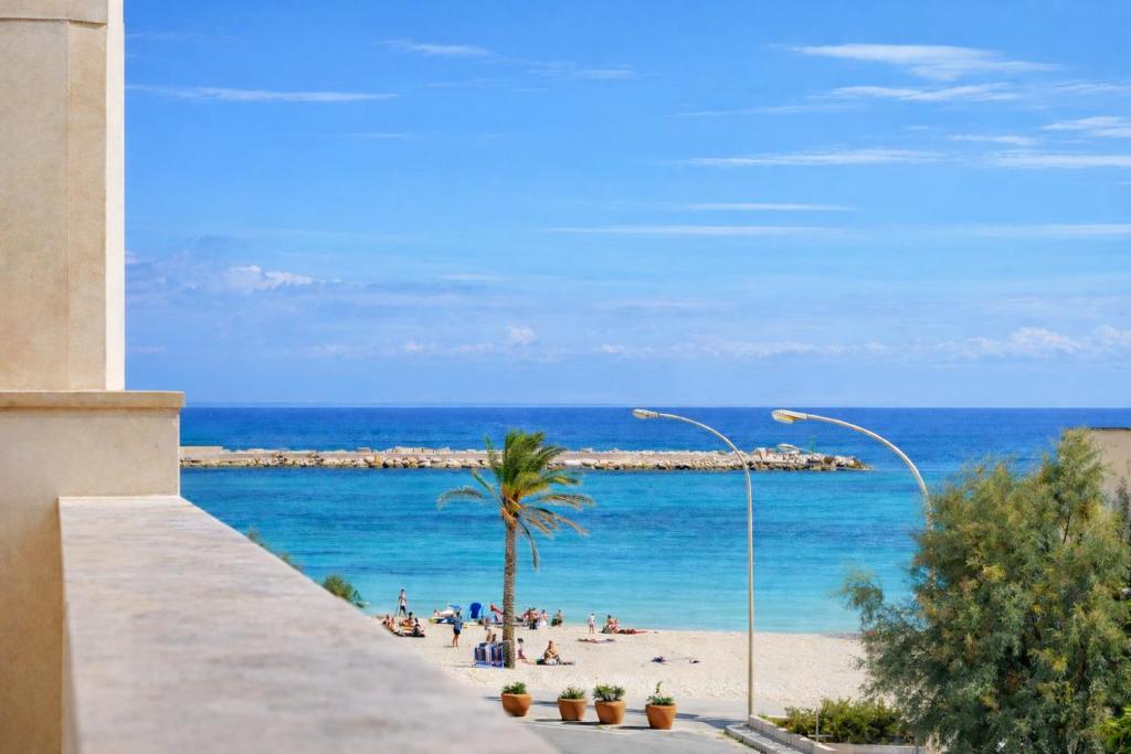 a view of a beach with a palm tree and the ocean at Araba Fenice Hotel in San Vito lo Capo