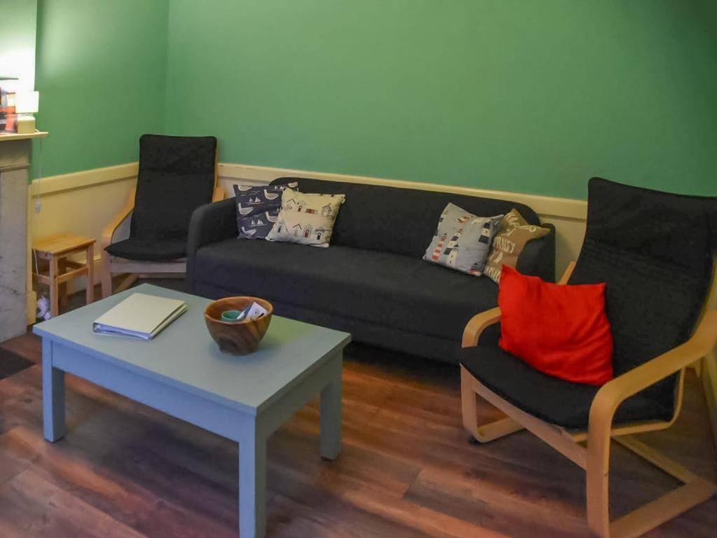 a living room with a couch and two chairs and a table at North Cottage in Lowestoft