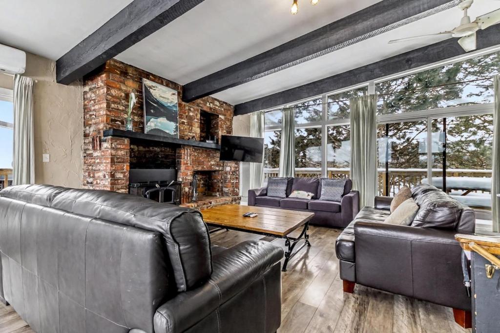 a living room with leather furniture and a brick wall at Mountain View-Backyard-Air-Conditioning-BBQ-15mins walk Blue Mountain Village in Blue Mountains